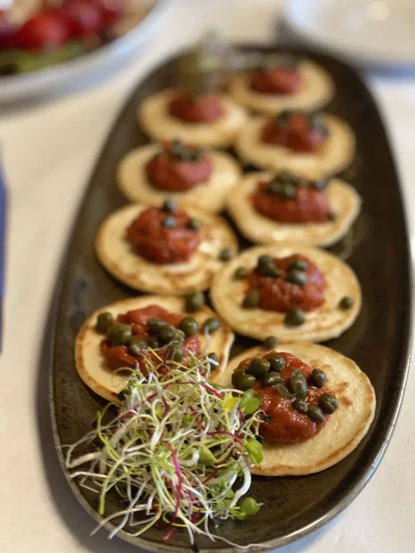 Mini-Blinis mit Thunfisch-Tatar, Kapern und frischen Sprossen als eleganter Apéro-Happen.