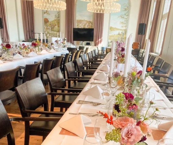 Festlich gedeckte Hochzeitstafel im Löwen-Saal mit leuchtenden Sommerblumen in Glasvasen.