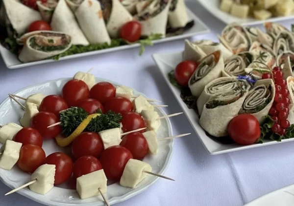 Frische Wraps und Tomaten-Mozzarella-Spiesse, garniert mit roten Johannisbeeren und Kräutern. Leichte Sommerküche im Grünen.