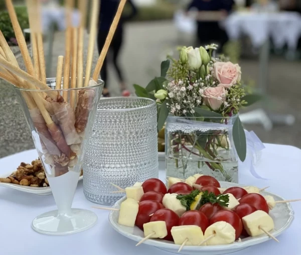 Eleganter Apéro mit Tomaten-Mozzarella-Spiessen, Grissini im Glas und zartrosa Rosen als Tischdekoration