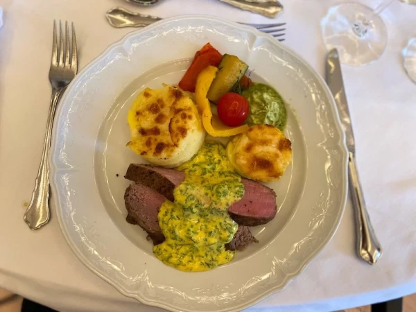 Rinderfilet rosa gebraten mit Kräuterbutter, dazu Kartoffelgratin und gegrilltes Gemüse.