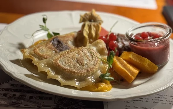 Hausgemachte Hirschfleisch-Piroggen, serviert mit Herbstbeilagen.