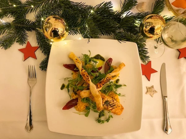 Weihnachtlicher Lachsteller mit knusprigen Teigstangen und Wintersalat. Festlich dekoriert mit Tannenzweigen und roten Sternen.