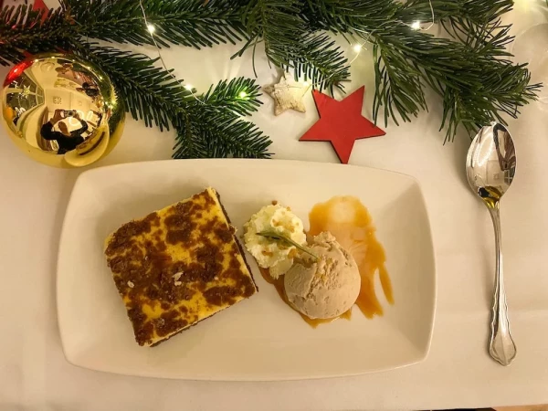 Weihnachtlicher Käsekuchen mit Vanilleeis unter geschmückten Tannenzweigen