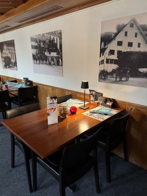 Modernes Sääli-Interieur mit historischen Schwarz-Weiss-Fotografien an den weissen Wänden über der Holzvertäfelung. 