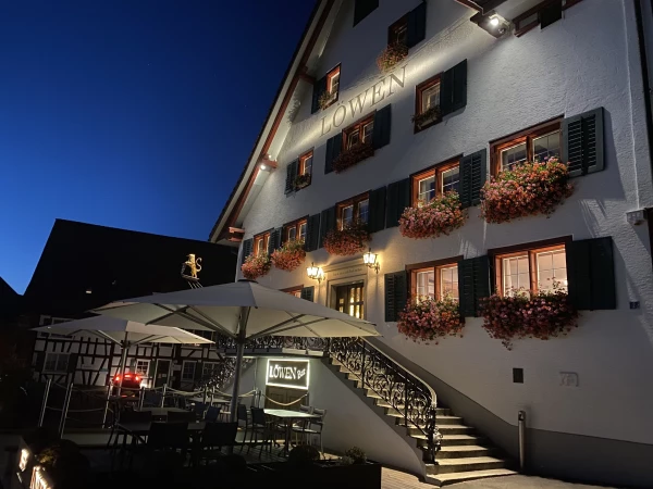 Abendansicht des Restaurant Löwen, ein traditionelles weisses Schweizer Gebäude mit beleuchteter Fassade.